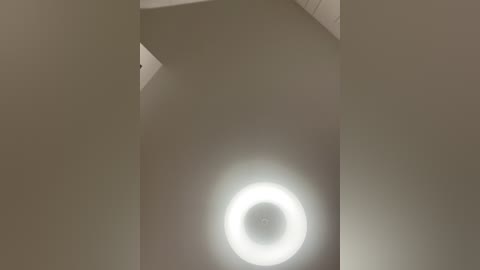 Media: Video of a minimalist interior with a stark white ceiling and a circular, bright white light fixture in the center. The image has a modern, clean aesthetic with no visible furniture or objects.