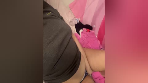 Media: Video of a woman's legs, wearing a black skirt, partially lifted, revealing pink panties. She sits on a pink blanket in a room with a pink curtain and pink wall.