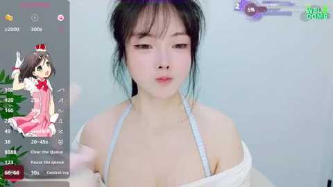 Media: Video of an Asian woman with fair skin, wearing a white off-shoulder dress, taken from a smartphone. Overlay shows a pink-haired anime character.