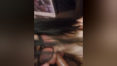 Media: Video of a close-up, blurred scene featuring a woman with long black hair, possibly engaged in sexual activity. The image is dimly lit with a focus on the woman's face and partially obscured body.