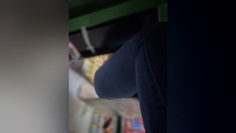 Media: A blurred video of a person's leg in dark blue jeans and white socks, partially visible through a green and dark blue striped curtain.