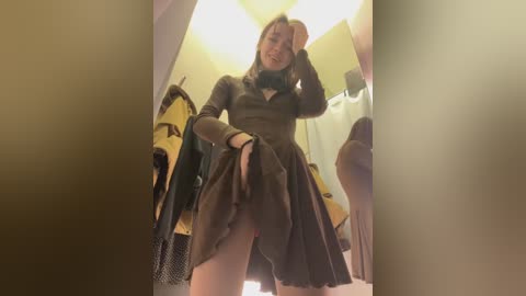 Media: Video of a woman in a dark brown, long-sleeved dress with a black bow, lifting her skirt to reveal her underwear. Background shows a cluttered closet with hanging clothes and a yellow jacket.