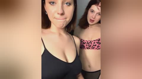 Media: A video of two women with fair skin, one in a black bra, the other in a leopard-print bra. The background is blurry, focusing on their faces and upper bodies.