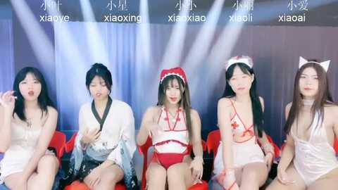 Media: Video of five East Asian women in revealing, festive costumes, sitting on red chairs in a dimly lit room, with bright lights and Chinese text in the background.