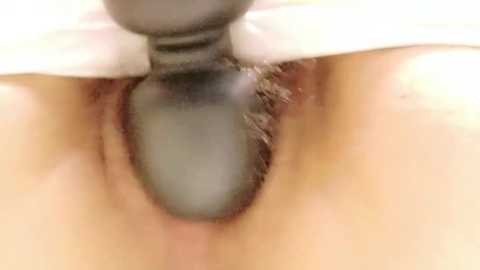 Media: Close-up video of a person's anus, with a greyish-white dildo being inserted. The skin tone is light. The background is blurred, focusing attention on the intimate act.