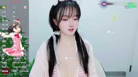 Media: Video of a young Asian woman with long black hair, wearing a pink and white striped top, standing in front of a white wall. A live-stream overlay shows a green background and a cartoon character.