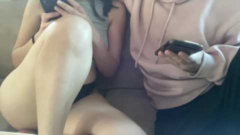 Media: A video captures two women in a close embrace, one wearing a light pink hoodie and the other a black top, both holding smartphones.