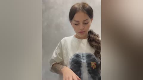 Media: Video of a young Latina girl with long dark hair, wearing a white T-shirt with a detailed Darth Vader graphic, standing in a dimly lit, blurry corridor.