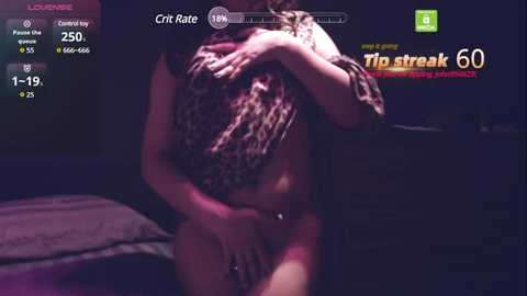 Media: A low-light video of a nude woman with fair skin, partially covered by a leopard-print blanket, holding her breasts and crotch. The background is dimly lit, suggesting an intimate, possibly bedroom setting.