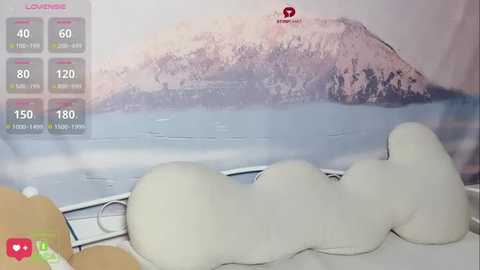 Media: Video of a woman reclining on a white leather couch, facing a serene mountainous lake scene on a large wall-mounted TV, with fitness stats displayed in the top left corner.