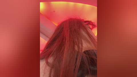 Media: Video of a woman with long, straight brown hair, seen from the back, under a red light, creating a warm, intimate atmosphere.