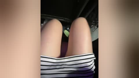 Media: Video of a person's bare legs, wearing black-and-white striped panties, reclined on a bed, with a blurred background.