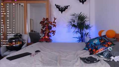 Media: Video of a Halloween-themed bedroom with a white bed, orange balloons, a bat wall decal, and a jack-o'-lantern pillow, with a TV showing \"Freddy vs. Jason\" playing.