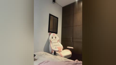 Media: A video of a minimalist bedroom with a white gaming chair, a framed mirror, and a closed wardrobe, showcasing a modern, clean aesthetic.