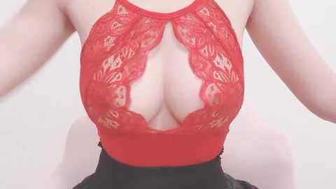 Media: Video of a fair-skinned woman wearing a revealing red lace bodysuit with cutouts, exposing cleavage, paired with black shorts.