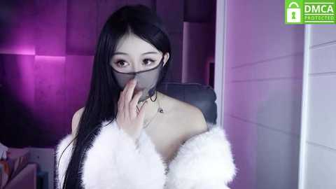 Media: Video of an East Asian woman with long black hair, wearing a white faux fur coat, black glasses, and a black face mask, in a dimly lit room with purple and pink lighting.