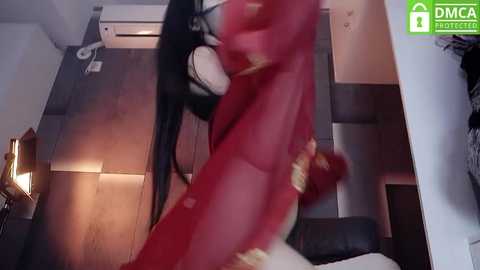 Media: A blurry video showing a woman with long black hair, wearing a red dress, and a man in a white shirt, engaged in a passionate kiss in a modern apartment with wooden floors.