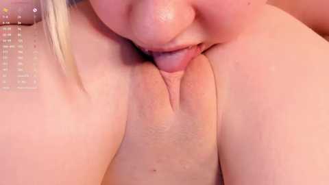 Media: Close-up video of a nude woman with fair skin performing oral sex on a male partner. The image focuses on their genitals, with the woman's tongue licking the man's penis.