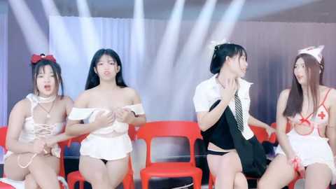 Media: Video of four Asian women in revealing nurse outfits and lingerie, seated on red plastic chairs in a dimly lit room.