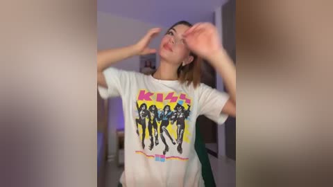 Media: A video of a young woman in a white t-shirt featuring the KISS logo, dancing joyfully indoors with a blurred background.