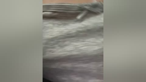 Media: A blurred, close-up video of a person's waist, wearing light grey, textured sweatpants with a drawstring. The image is out of focus, making it difficult to discern further details.