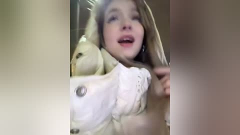 Media: Video of a young woman with blonde hair, wearing a white lace bra, surrounded by stuffed animals in a dimly lit room.