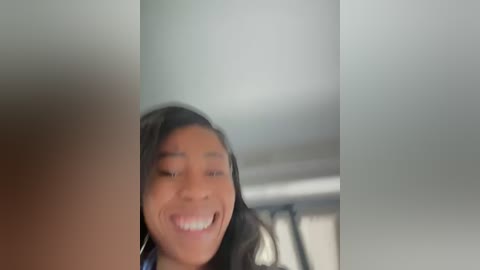 Media: A blurred video of a young, happy African-American woman with long dark hair, smiling widely. She's partially obscured by a blurry, light-colored background.