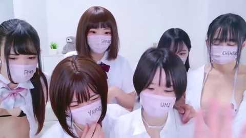 Media: Video of five Asian women in medical masks, white lab coats, and white tops, seated in a sterile, white room.