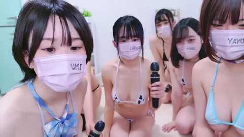 Media: Video of five Asian women in a white room, wearing face masks and revealing lingerie, holding vibrators, in a suggestive pose.