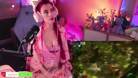 Media: A composite image of a young woman with fair skin and red hair, wearing headphones and a pink robe, livestreaming on a gaming chair. Background includes plush toys and a gaming setup.