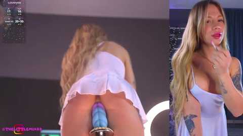 Media: Video of a blonde woman with long hair, wearing a white dress, bent over a blue dildo in a dimly lit room.