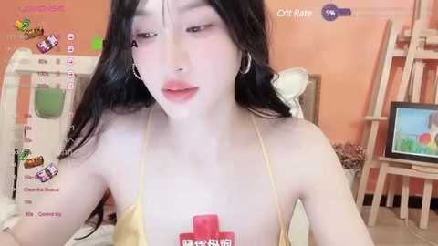 Media: Video of an Asian woman with long black hair, wearing a yellow bikini, standing in a bedroom with a TV, a shelf, and a bed.