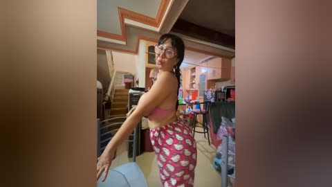 Media: Video of an Asian woman in a pink pajama set with white hearts, posing in a cluttered basement.