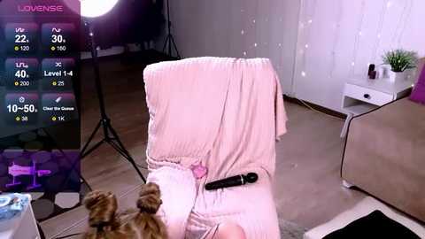 Media: Video of a cozy living room with a pink blanket draped over a chair, a cat sitting nearby, and a large screen displaying a \"LoveSense\" app interface.