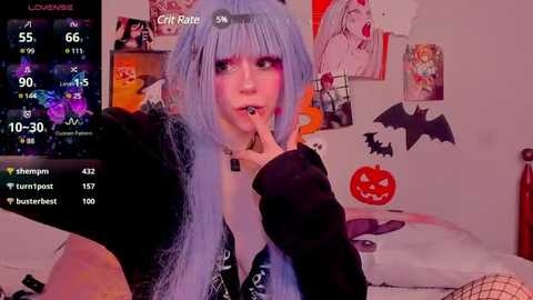 Media: Video of a pale-skinned woman with blue hair, wearing a black jacket, and fishnet stockings, in a Halloween-themed bedroom, with various posters and decorations, including a jack-o'-lantern.