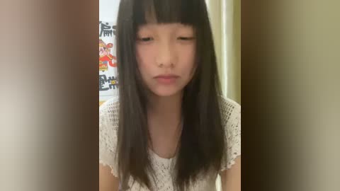 Media: Video of an Asian girl with long black hair, wearing a white crochet top, pouting in a doorway with colorful posters in the background.