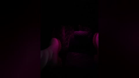 Media: A dimly lit, close-up video of a hand reaching into a dark space, with purple and pink hues casting an eerie glow.