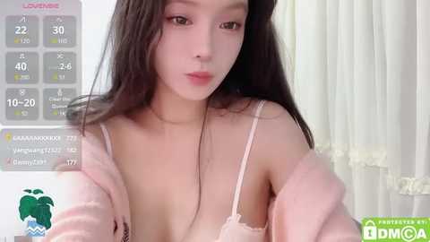 Media: Video of an East Asian woman with long black hair, wearing a pink robe, revealing a pink bra, in a bedroom with white curtains.