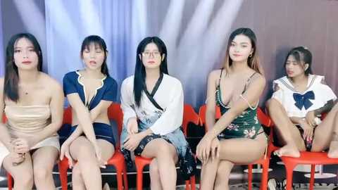 Media: Video of five Asian women in provocative, revealing outfits sitting on red chairs against a grey and white backdrop.