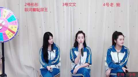 Media: Video of three young Asian women in blue Adidas tracksuits, sitting on chairs, holding microphones, speaking against a white backdrop.