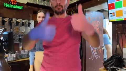 Media: Video of a bearded man in a red shirt giving a thumbs-up in a dimly lit bar. Bar taps, beer posters, and a Heineken sign are visible in the background.