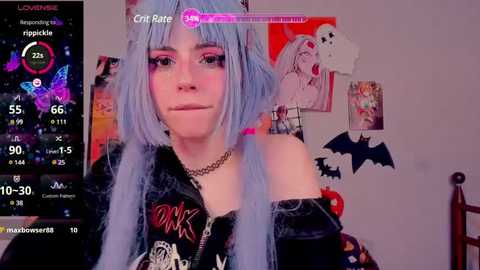 Media: A young woman with pale skin, long blue hair, and a black choker poses in a bedroom adorned with anime posters and a bat decoration. She wears a black jacket and looks into the camera.