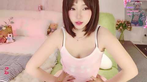 Media: A video of a young Asian woman with a petite frame, wearing a white tank top, sitting on a green sofa in a cozy, softly lit room.