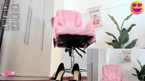 Media: Video of a pink ergonomic office chair with a high backrest, positioned on a wooden floor in a minimalist room with white walls and a potted plant.