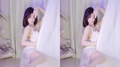 Media: Video of an Asian woman with shoulder-length black hair, fair skin, and medium breasts, wearing a white lace lingerie set, sitting on a cushioned chair. She's surrounded by sheer curtains in a dimly lit room.