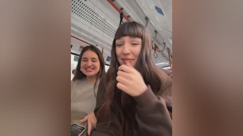 Media: Video of two young women in a train, one with long brown hair, smiling, and the other with medium-length dark hair, laughing, in casual attire.