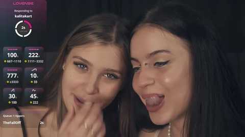 Media: A video of two young women with light skin and long hair, one with brown hair and the other with black hair, smiling and sticking out their tongues.