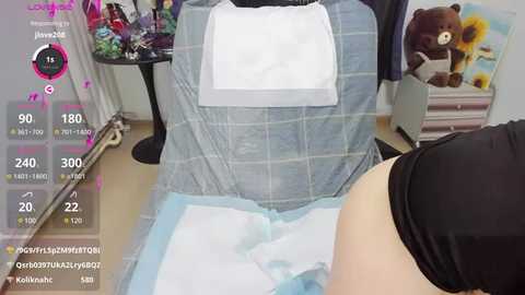 Media: Video of a person sitting on a dental chair with a blue gown, white bib, and a black sleeve, surrounded by dental tools and a teddy bear on a wooden floor.