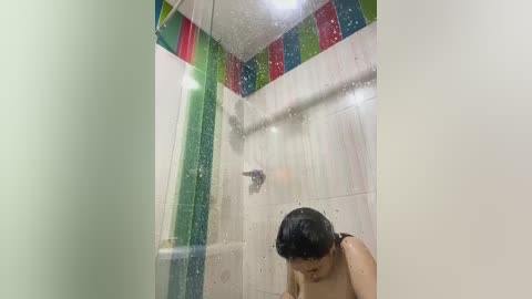 Media: Video of a young Asian woman with wet hair, taking a shower in a brightly colored, tiled bathroom. The image is slightly blurred and out of focus, emphasizing the wetness and steam.