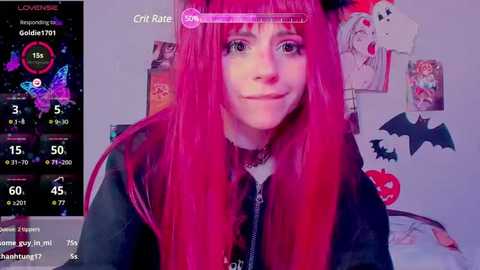 Media: A video of a young woman with long, bright pink hair, wearing a black jacket and a choker, smiling in a bedroom adorned with Halloween-themed decorations, including a bat poster.